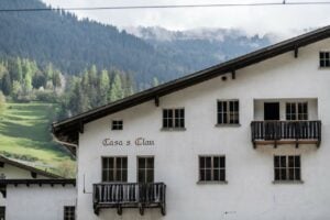 Gruppenhaus Sample House in City of Sample, weißes Gebäude mit Balkonen und Bergen im Hintergrund
