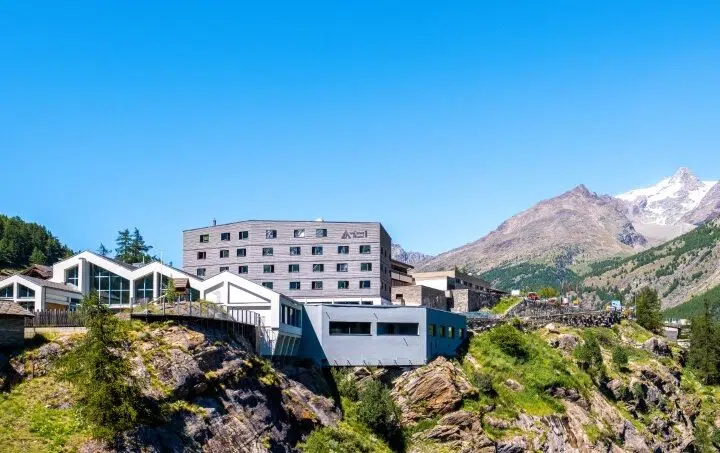 Gruppenhaus Saas-Fee Wellness Hostel 4000 auf Bergklippe mit Bergpanorama im Hintergrund