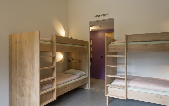 Gruppenhaus Saas-Fee Wellness Hostel 4000, Doppelstockbetten in Zimmer mit lila Wänden
