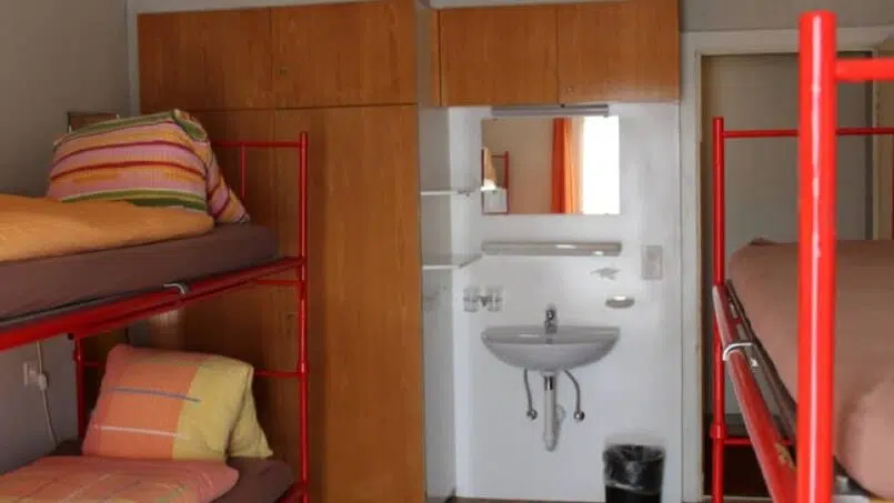 Kleines Zimmer mit Etagenbetten und Waschbecken im Adrenalin Backpackers Hotel Braunwald, Gruppenunterkunft
