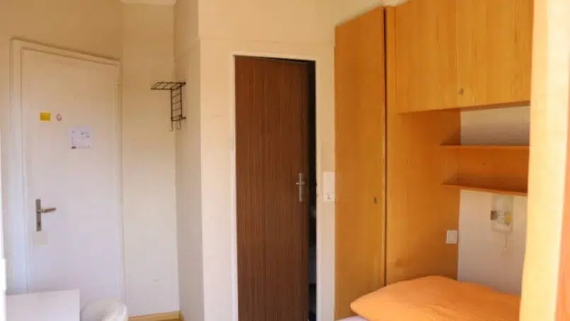 Kleines Zimmer mit Bett und Schreibtisch im Adrenalin Backpackers Hotel Braunwald, beliebte Gruppenunterkunft in Braunwald