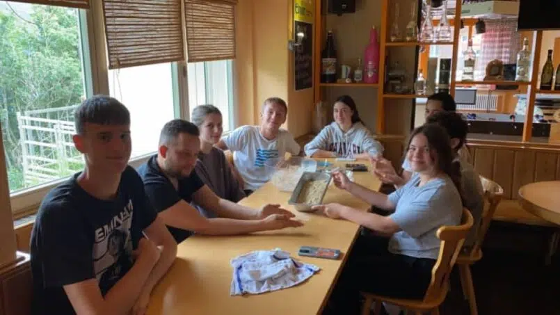 Gruppe von Menschen sitzt im Restaurant des Adrenalin Backpackers Hotel Braunwald, Gruppenunterkunft in Braunwald