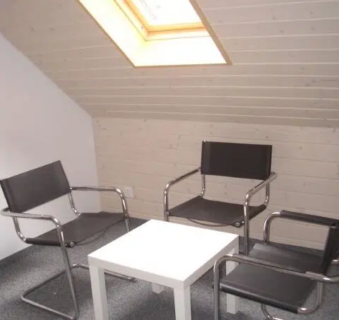 Gruppenunterkunft Alpenblick Schwarzenegg - Zimmer mit schwarzen Stühlen und Tisch unter Dachfenster