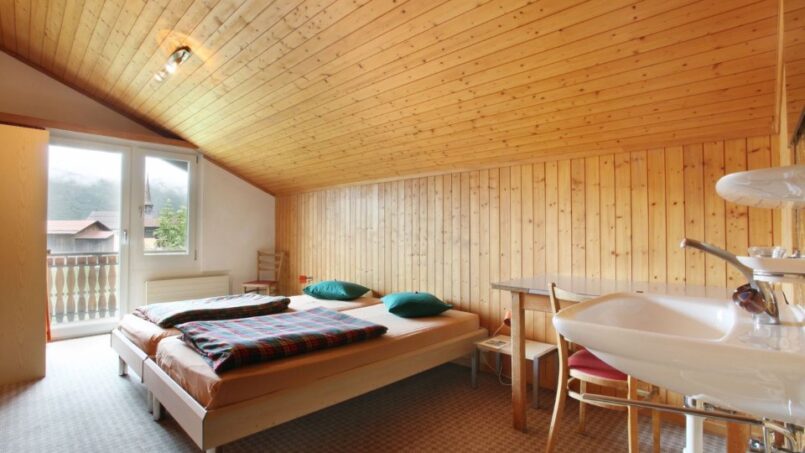 Schlafzimmer im Gruppenhaus Alpina Segnas mit Bett und Waschbecken