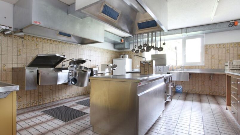 Großzügige Küche Gruppenhaus Alpina Segnas in Disentis mit Edelstahlgeräten und gefliestem Boden