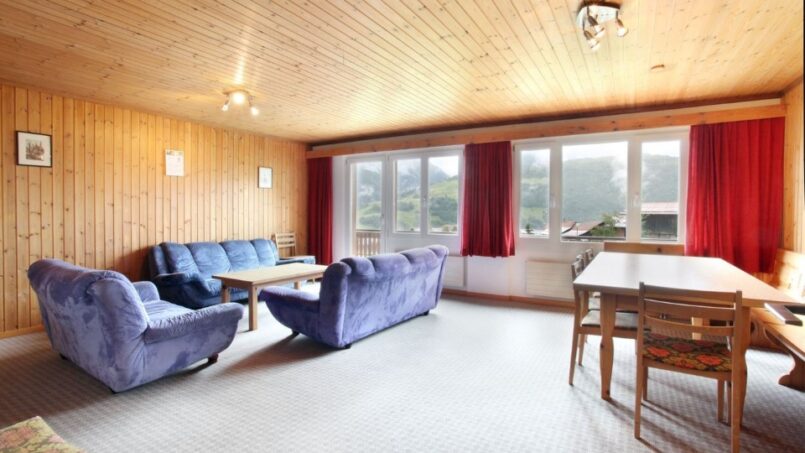 Gruppenhaus Alpina Segnas, rustikales Wohnzimmer mit Holzwänden und -möbeln in Segnas Disentis