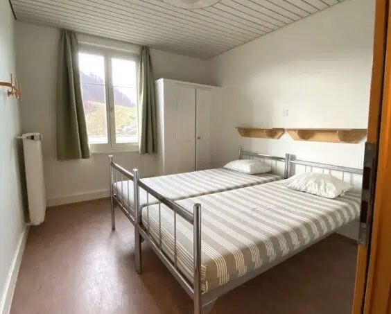 Gruppenhaus Baselbieter Kinderhaus Langenbruck - kleines Zimmer mit zwei Betten und Fenster