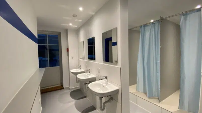 Gruppenhaus Baselbieter Chinderhus Langenbruck Badezimmer mit zwei Waschbecken und blauem Vorhang