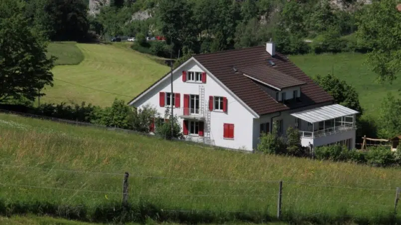 Gruppenhaus Baselbieter Chinderhus Langenbruck - weisses Haus mit roten Fensterläden auf einem Hügel