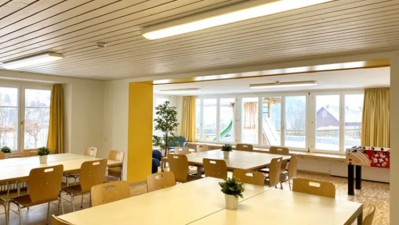 Gruppenhaus Baselbieter Chinderhus in Langenbruck - Zimmer mit Tischen und Stühlen und gelben Wänden