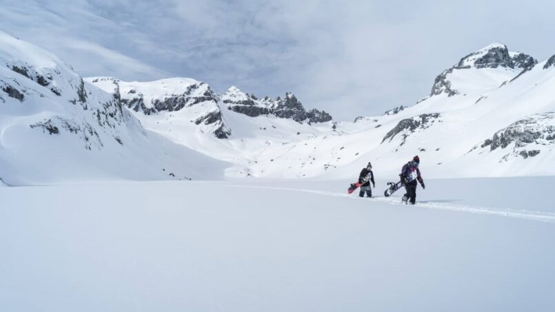 Zwei Personen wandern durch verschneite Landschaft vor Berghaus Nagens Gruppenhaus in Flims