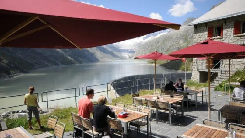 Gruppenhaus Berghaus Oberaar in Guttannen - Restaurant mit Tischen und Sonnenschirmen am Seeufer