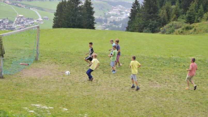 Kinder spielen Fußball am Berghaus Planatsch Gruppenhaus in Sedrun