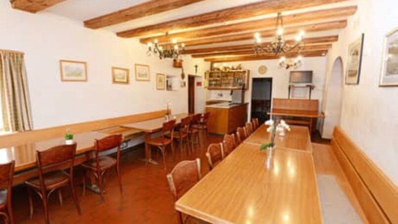 Restaurant im Gruppenhaus Casa Mirella in Breil/Brigels mit Holztischen und -stühlen