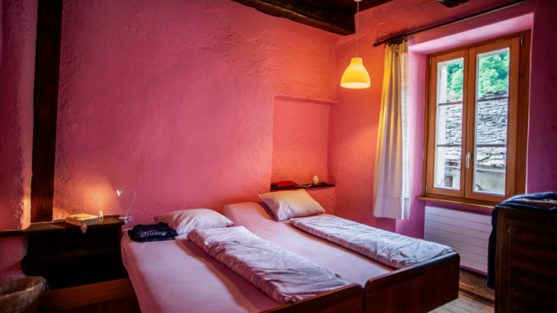 Zwei Betten in Gruppenunterkunft Casa Antica Lavizzara mit rosa Wänden