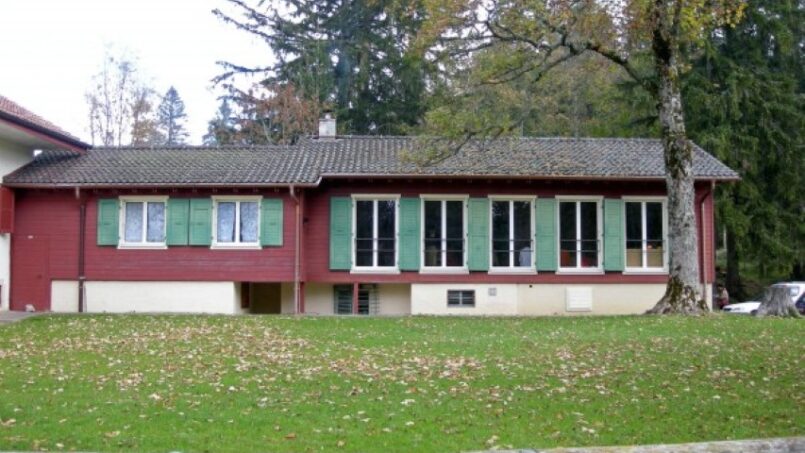 Rotes Gruppenunterkunft Haus Colonie du Creux-des-Biches mit grünen Fensterläden in Le Noirmont