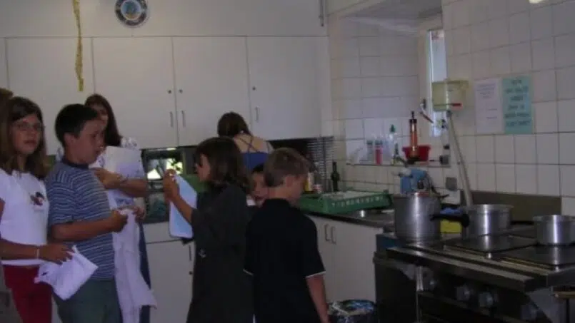 Gruppe von Menschen in der Küche der Gruppenunterkunft Colonie du Creux-des-Biches in Le Noirmont