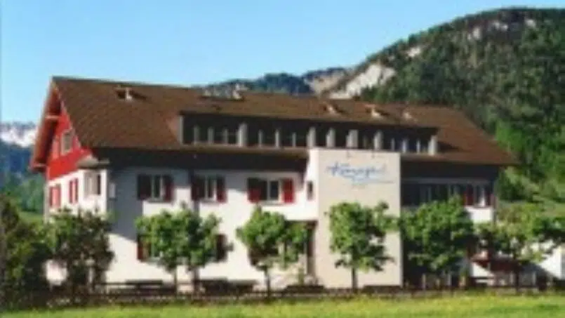 Gruppenunterkunft Erlebnisgästehaus Kanisfluh mit rotem Dach in Bezau vor Berglandschaft