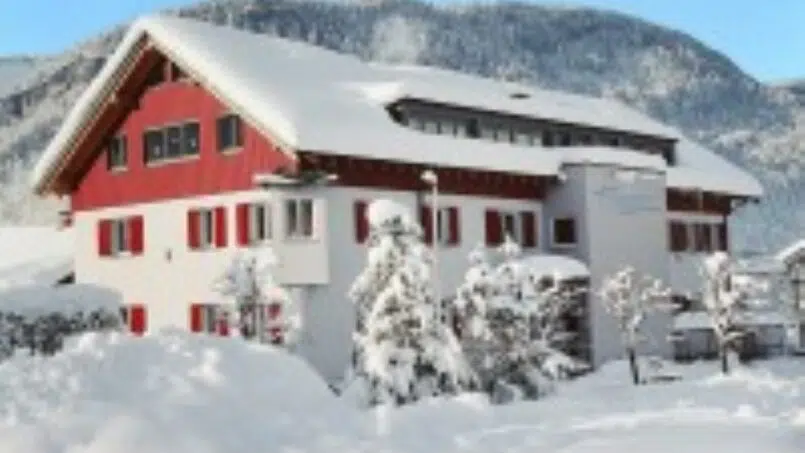 Gruppenunterkunft Erlebnisgästehaus Kanisfluh in Bezau mit rotem Dach im Schnee