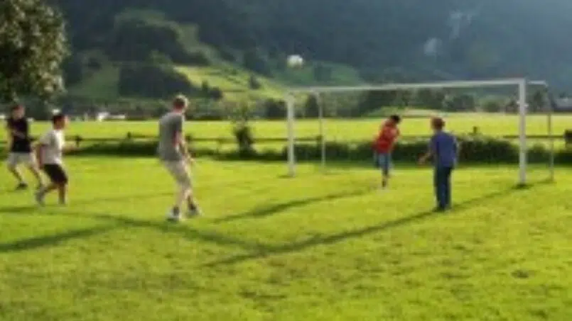 Gruppe spielt Fußball im Gras vor Gruppenunterkunft Erlebnisgästehaus Kanisfluh in Bezau