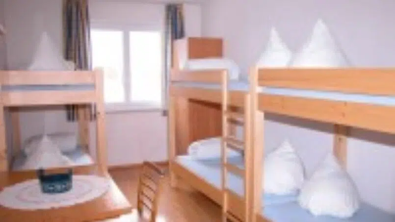 Kleines Zimmer mit Etagenbetten und Tisch im Erlebnisgästehaus Kanisfluh, Gruppenunterkunft in Bezau