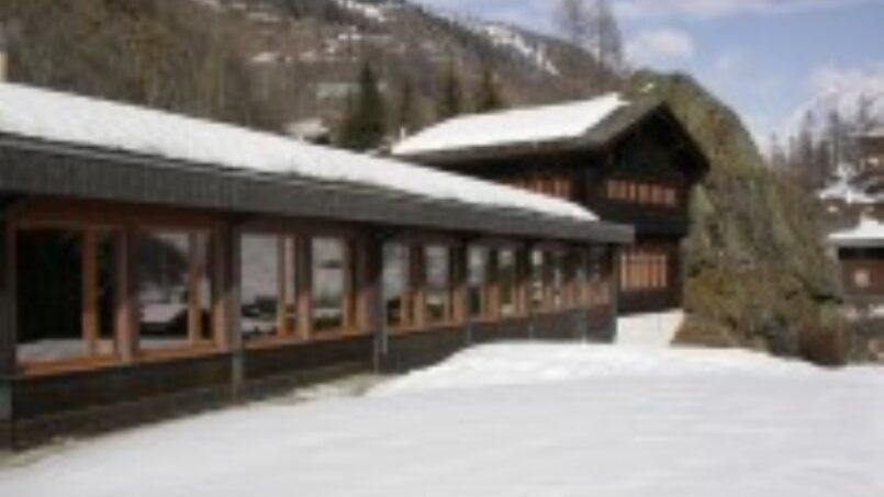 Gruppenunterkunft Ferien- und Gruppenhaus Blatten mit schneebedecktem Dach auf einem Hügel