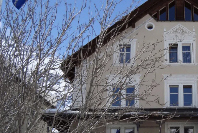 Ferienhaus Lenzburg Gruppenunterkunft im Ort Samedan mit hellbrauner Fassade und blauem Himmel