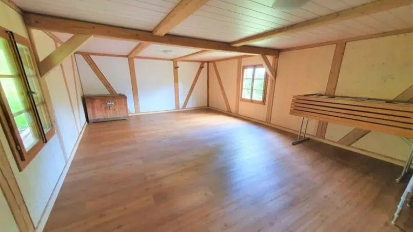 Leeres Zimmer mit Holzböden und Holzbalken im Ferienhaus Melli, Gruppenunterkunft in Wyssachen
