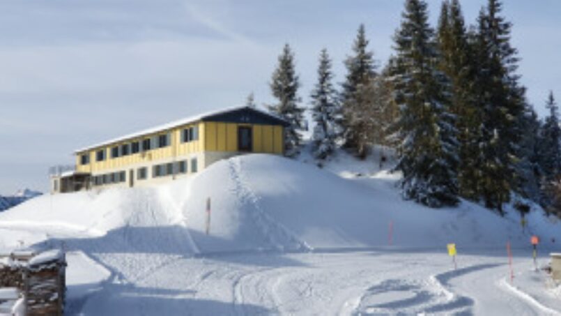 Gruppenunterkunft Ferienheim Schrattenblick Marbach - gelbes Gebäude auf schneebedecktem Hügel