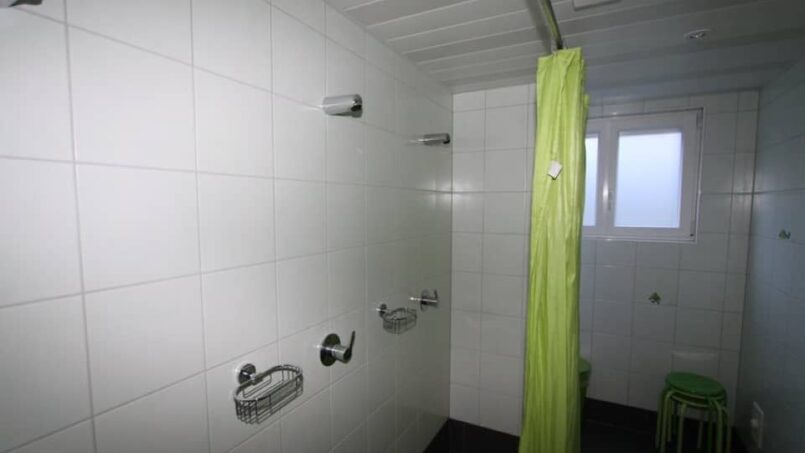 Grüner Duschvorhang im Badezimmer der Gruppenunterkunft Ferienlager Putnengia in Rueras