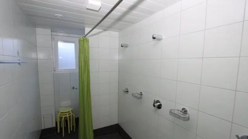 Grüner Duschvorhang im Badezimmer Gruppenunterkunft Ferienlager Putnengia Rueras