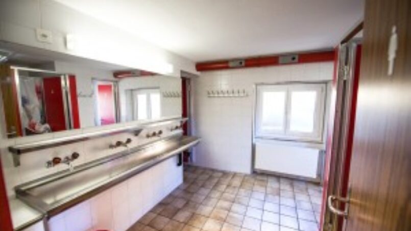 Rotes Waschbecken und Spiegel im Badezimmer der Gruppenunterkunft Ferienlager Splügen in Splügen