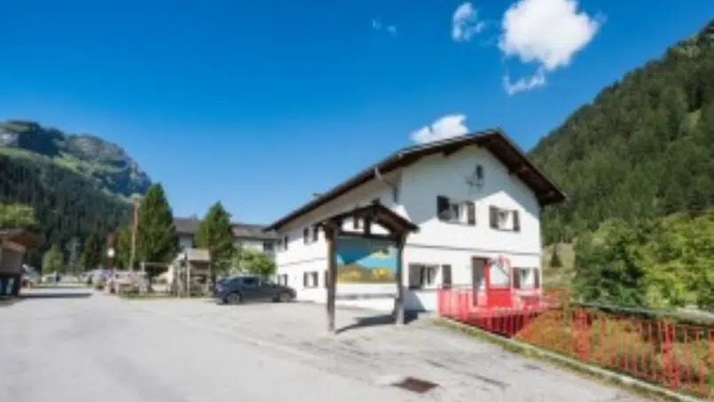 Gruppenunterkunft-Ferienlager-Splügen-Haus-in-den-Bergen-mit-rotem-Dach