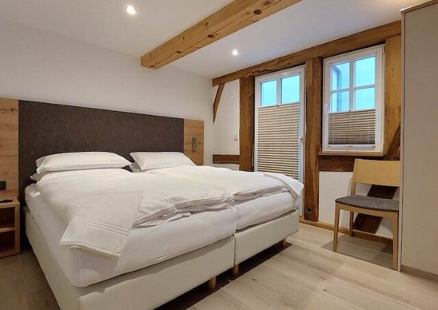 Gruppenunterkunft Gasthaus Ochsen Stein Schlafzimmer mit Holzbalken und weißem Bett
