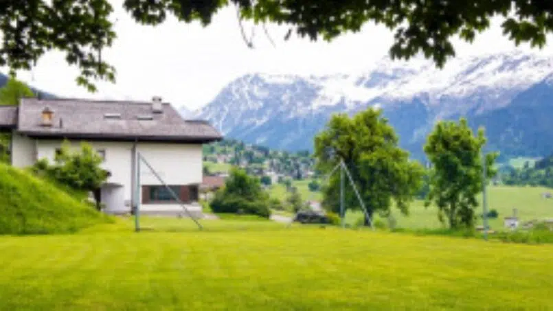 Gruppenunterkunft Gruoberhus Klosters-Dorf Haus im grünen Feld mit Bergen im Hintergrund
