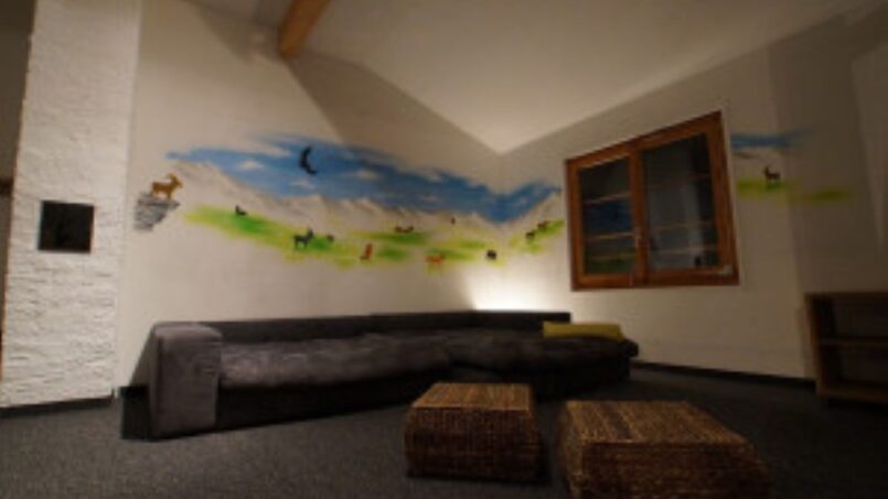 Gruppenunterkunft Hotel Rheinquelle Sedrun, Wohnzimmer mit Wandgemälde