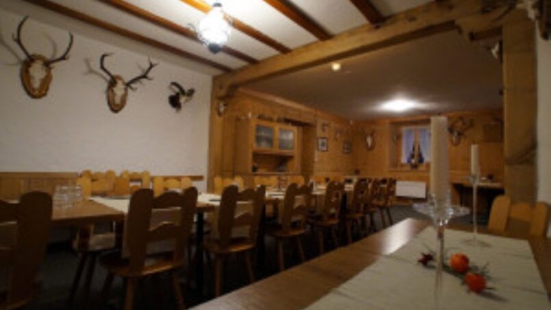 Gruppenunterkunft Holz-Esszimmer im Gruppenhaus-Hotel Rheinquelle in Sedrun mit Hirschgeweihen an den Wänden