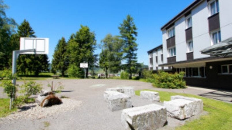 Steinbank vor Gruppenhaus SJBZ in Einsiedeln mit Basketballkorb