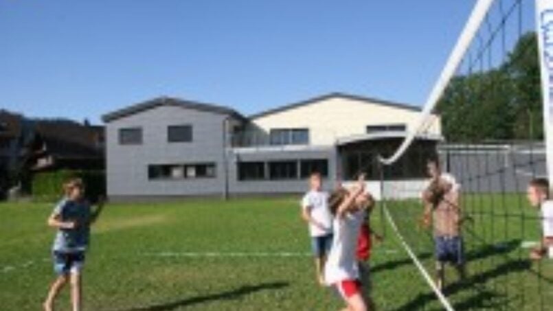 Kindergruppe spielt Volleyball auf grüner Wiese Gruppenunterkunft Haus an der Emme in Schüpfheim