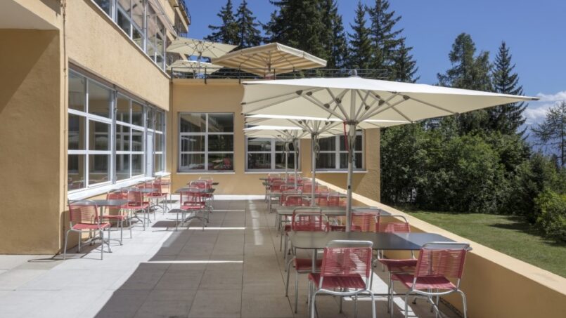 Jugendherberge-Crans-Montana-Balkon-mit-Stühlen-und-Sonnenschirmen