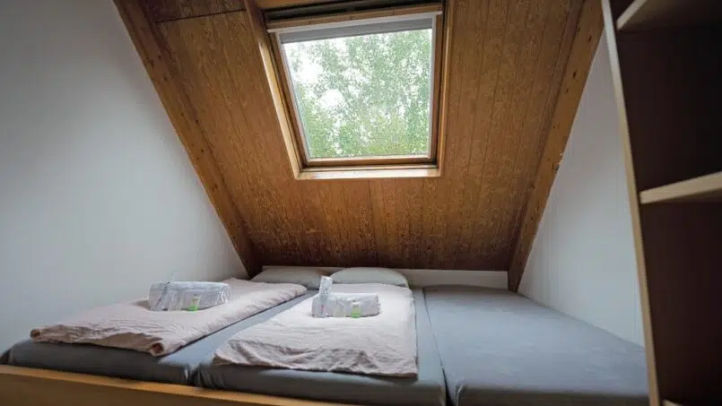 Zwei Betten im Dachzimmer der Jugendherberge Delémont mit Dachfenster