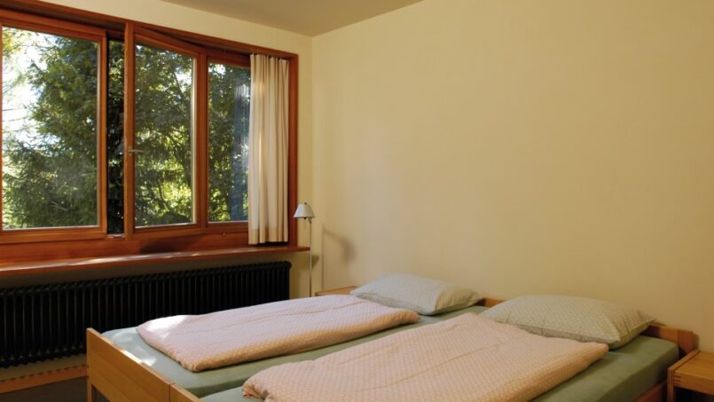 Zwei Betten in einem Zimmer der Jugendherberge Grindelwald mit Fensterblick
