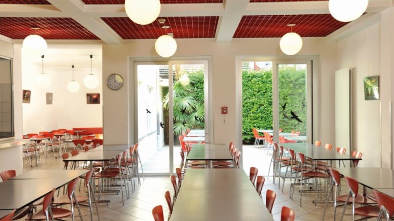 Jugendherberge Locarno Cafeteria mit roten Tischen und Stühlen