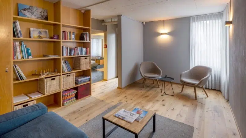 Wohnzimmer mit Bücherregalen und Couch in der Jugendherberge Luzern