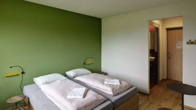 Zimmer in der Jugendherberge Schaan-Vaduz mit grüner Wand und zwei Betten