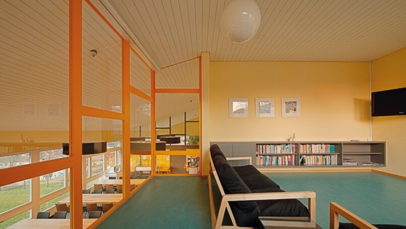Jugendherberge St. Gallen: orange-gelbes Zimmer mit Couch und Buchregalen.