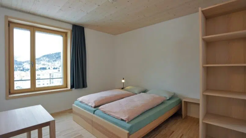 Kleines Zimmer mit Bett und Bücherregal in der Jugendherberge St. Moritz-Bad