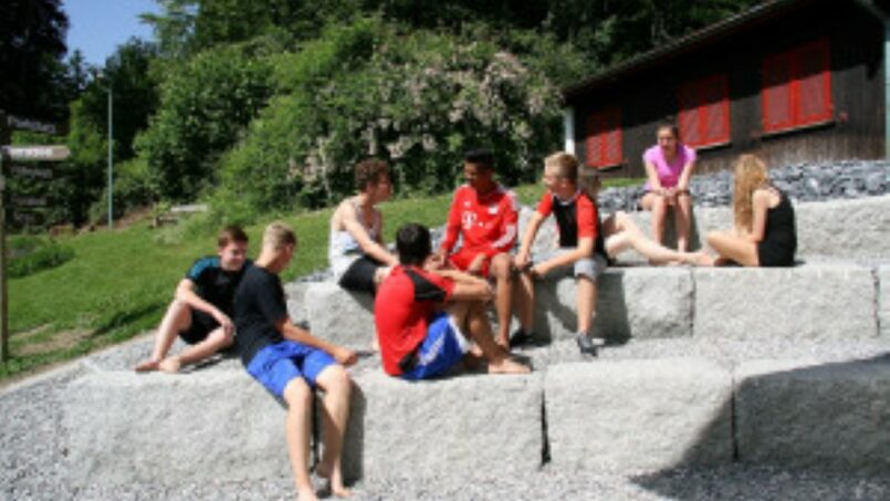 Gruppe von Menschen sitzt auf Felsen vor dem Jugend- und Erlebnishaus Eichberg, Gruppenunterkunft in Eichberg