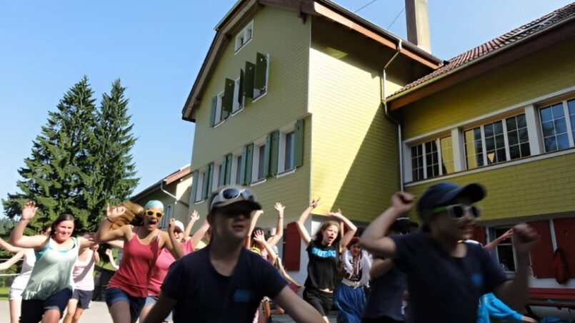 Gruppe tanzt vor Gruppenunterkunft Jugendalp Eigenthal
