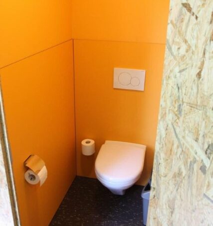 Gruppenunterkunft Jugendhaus Don Bosco Himmelried Badezimmer mit orangefarbener Wand und Toilette
